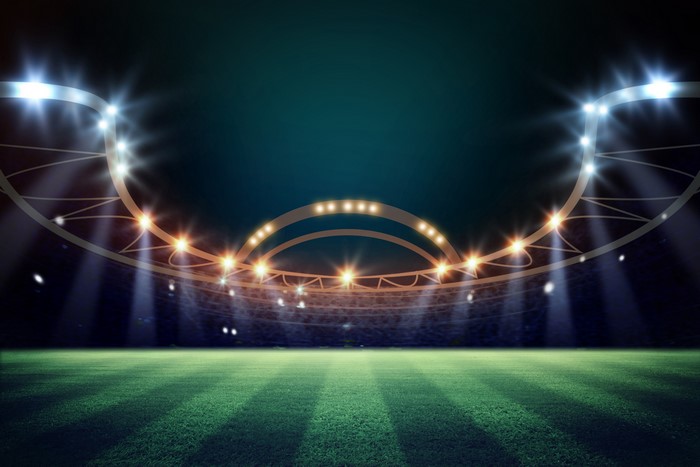 Stadium at night with bright lights and green field