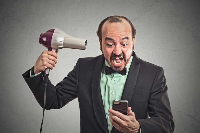 Man with hair dryer screaming at phone