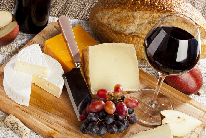Wine, Cheese, Grapes, and Bread on a Cutting Board