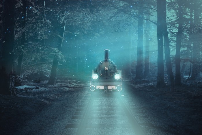 Train on railroad tracks in a foggy forest