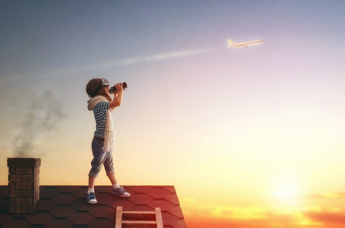 Boy with binoculars on roof watching airplane