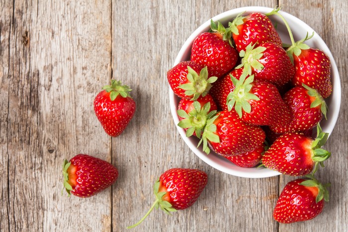 Strawberries in a bowl on wood planks