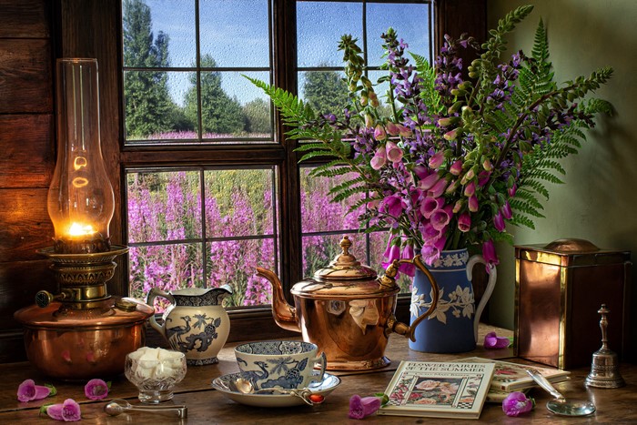Still life with kerosene lamp, tea set, and flowers by the window
