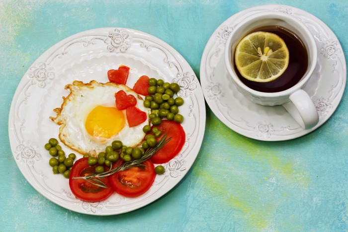 Fried egg with tomatoes, peas, and tea