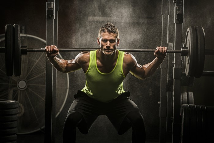 Man performing barbell squats in a gym