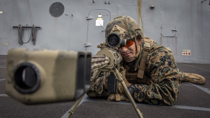 Marine aiming a sniper rifle on a ship deck