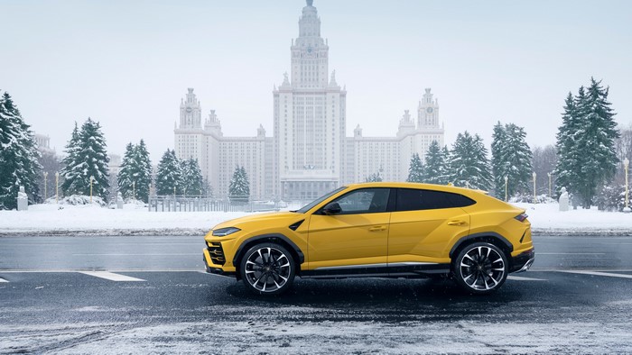 Yellow Lamborghini Urus in front of a snowy building