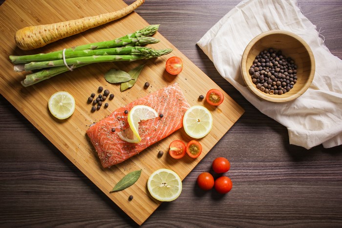 Salmon with Asparagus, Lemon, and Tomatoes on Cutting Board