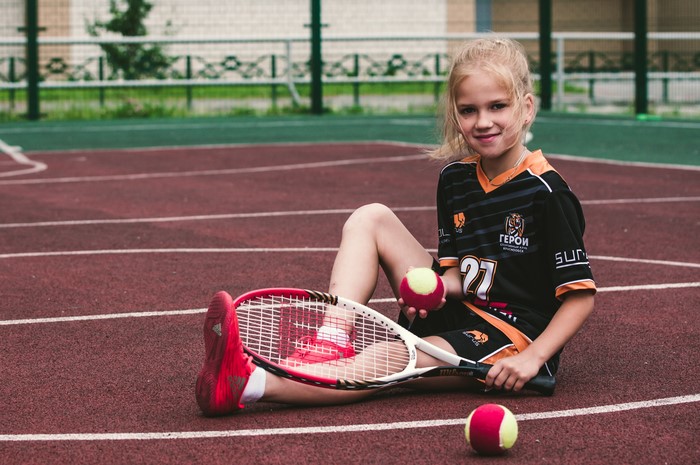 Girl with Tennis Racquet and Balls on Court