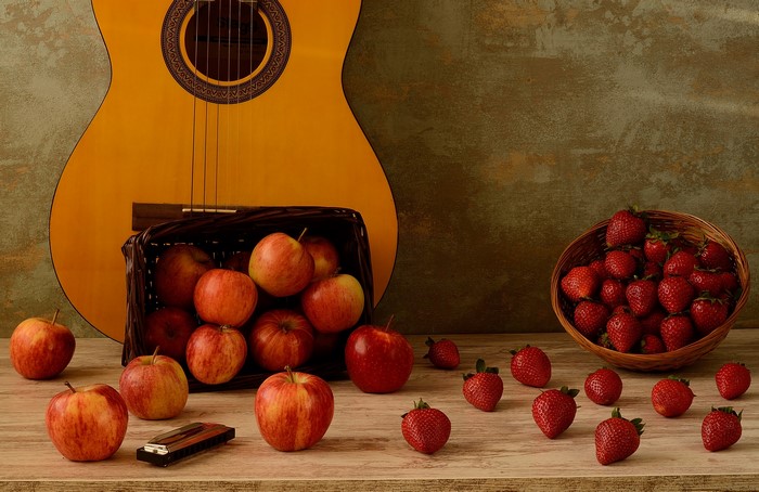 Still life with guitar, apples, strawberries, and harmonica