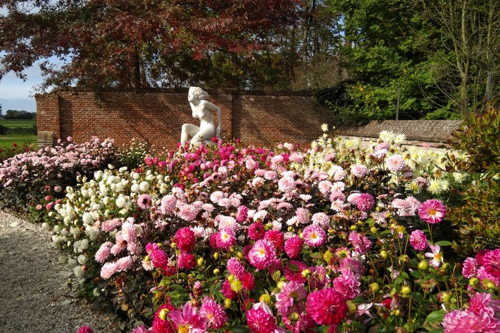 Garden with Dahlias, Sculpture, and Brick Wall in Lisse
