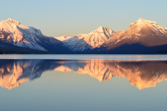 Snow-capped mountains reflected in a calm lake at sunrise