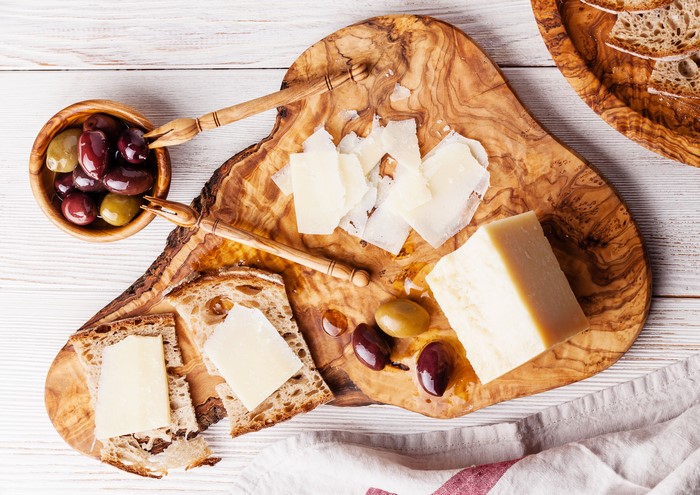 Cheese and olives on a wooden cutting board with bread