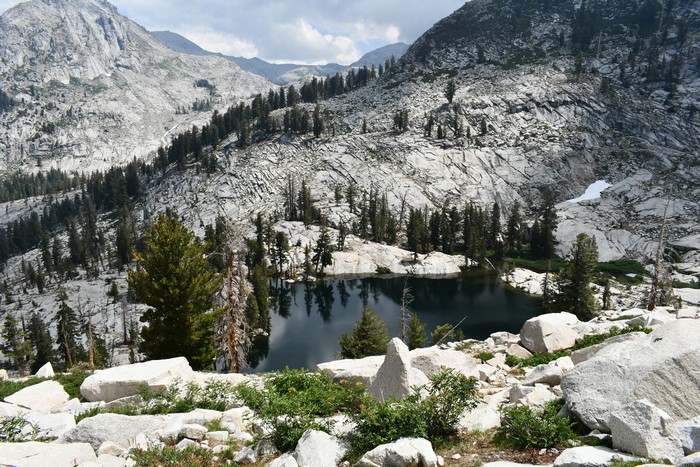 Lake surrounded by rocky mountains and pine trees in Sequoia National Park