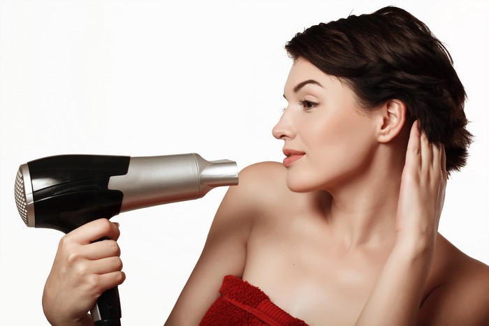 Brunette girl drying hair with hair dryer