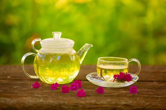 Glass teapot and cup of tea with flowers