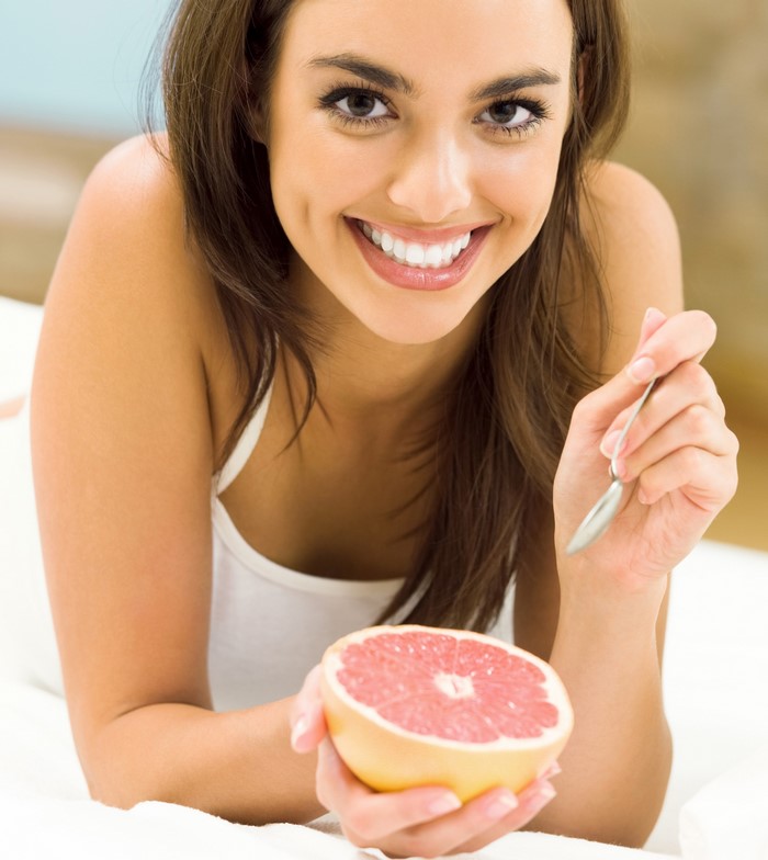 Woman smiling with grapefruit and spoon