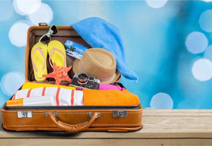 Open suitcase packed for vacation with beach items