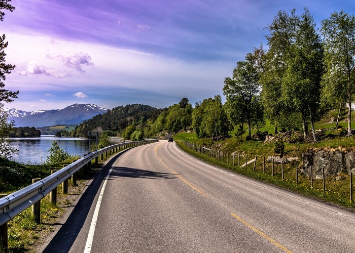 Curving road by a lake with mountains and trees