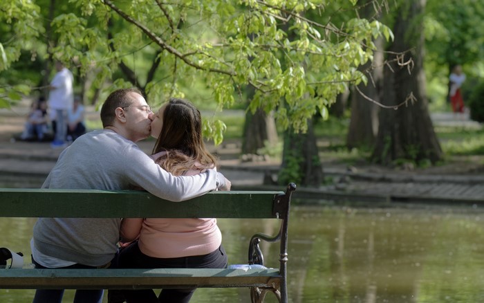 Couple kissing on a park bench