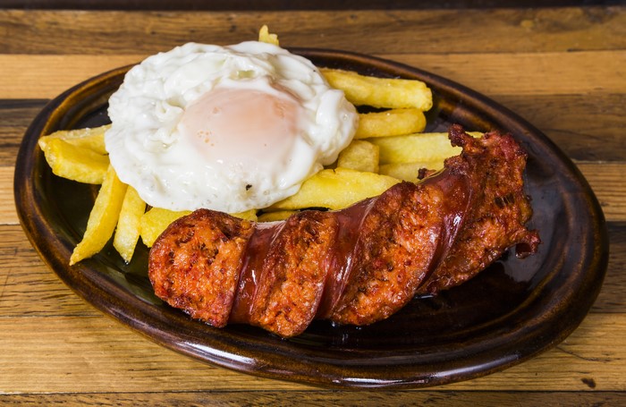 Fried egg with sausage and french fries on a plate
