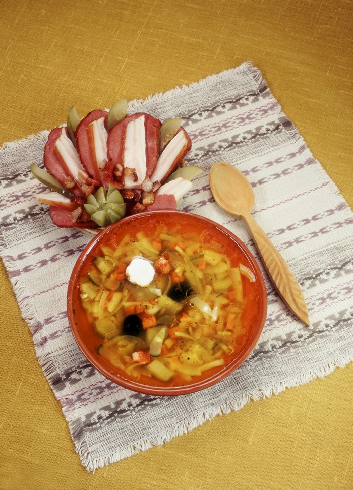 Soup and meat platter with spoon on tablecloth