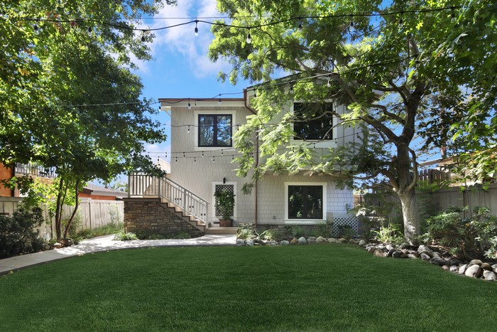 Modern house with a backyard lawn and trees