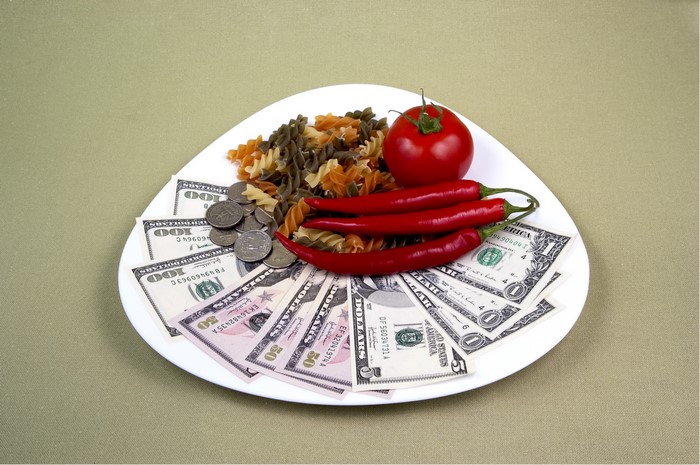 Plate of pasta, chili peppers, tomato, coins, and US dollars