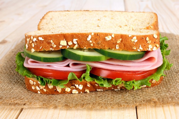 Sandwich with ham, tomato, cucumber, and lettuce on whole wheat bread