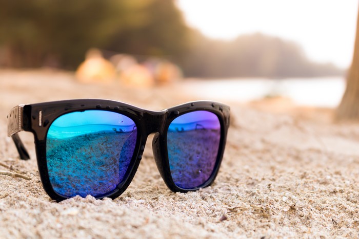 Black sunglasses with blue and purple lenses on sand