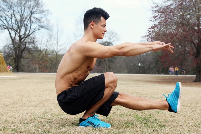 Man performing a pistol squat outdoors