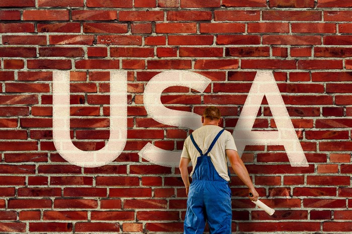 Man painting USA on a brick wall
