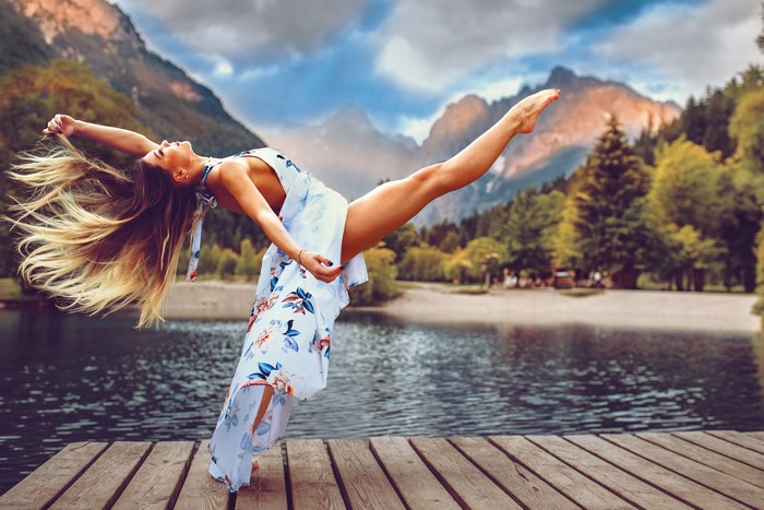 Woman in floral dress dancing on a dock