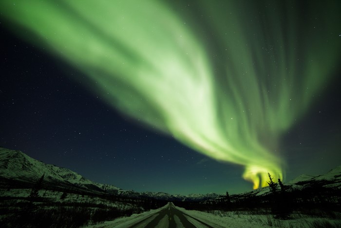 Aurora Borealis over a snowy road at night