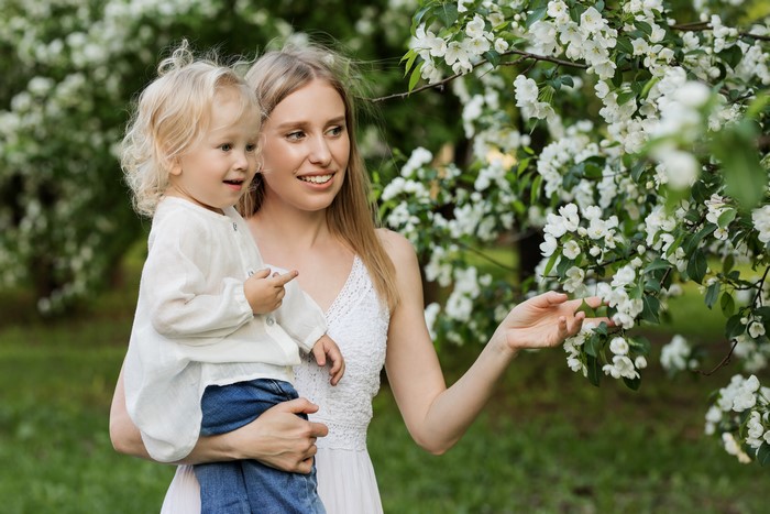 Mother holding a child near flowering trees