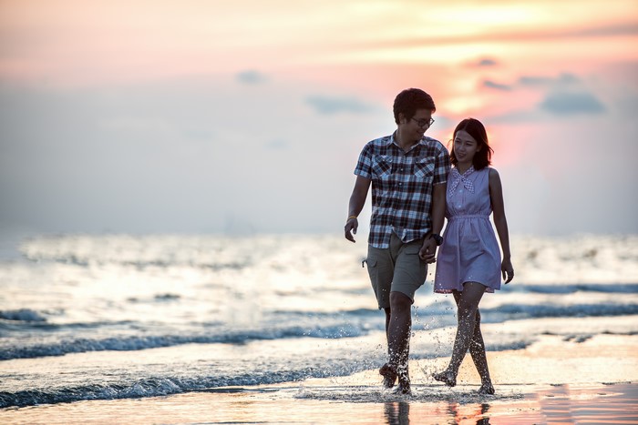 Couple walking on beach at sunset