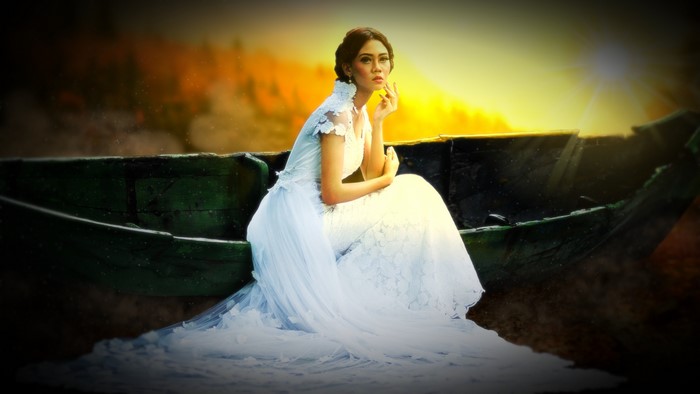 Bride in a white dress sitting in a boat