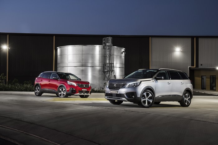 Two Peugeot SUVs parked outside a building
