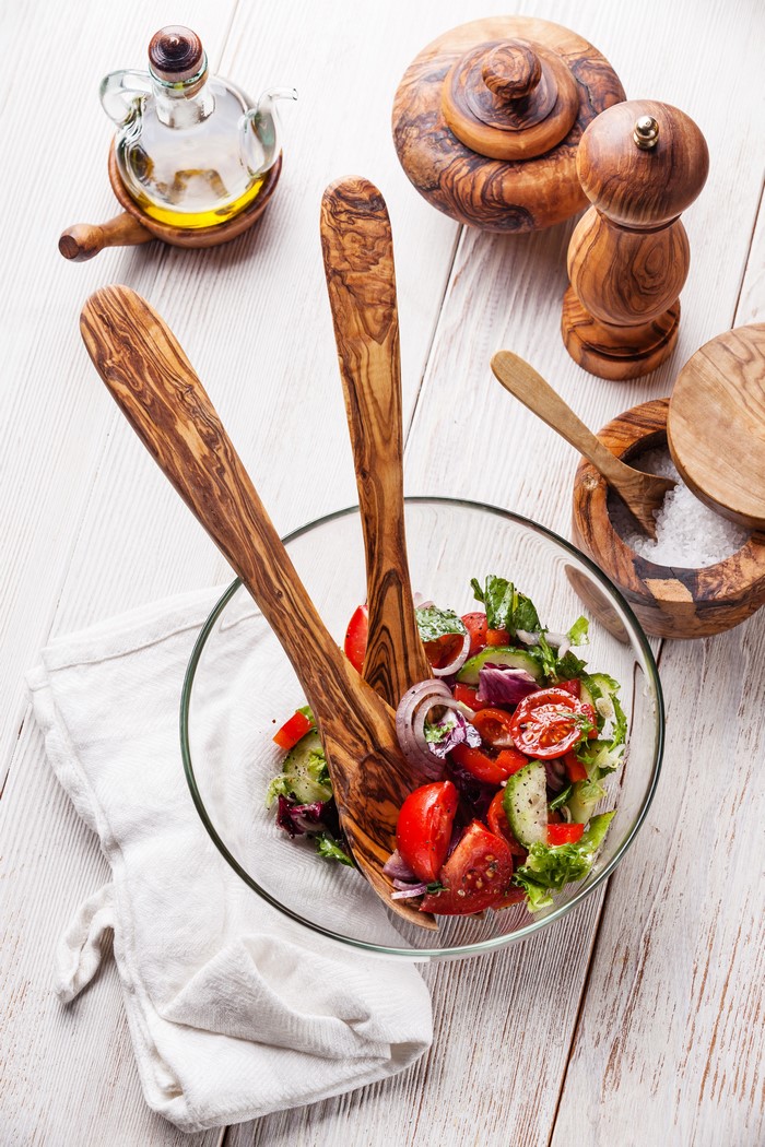Salad with wooden utensils and olive oil