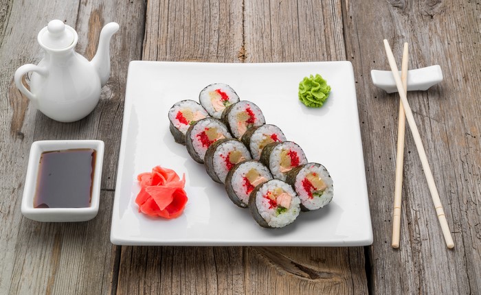 Sushi rolls with wasabi, ginger, soy sauce, and chopsticks on wood