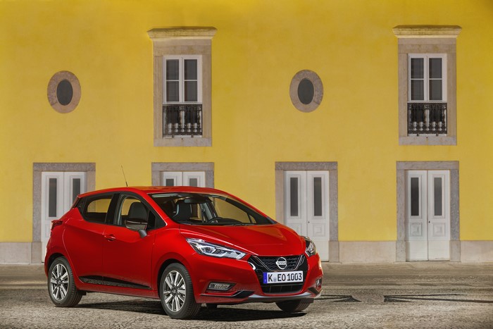 Red Nissan Micra in front of yellow building