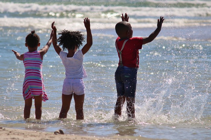Three children playing in the sea with water splashes