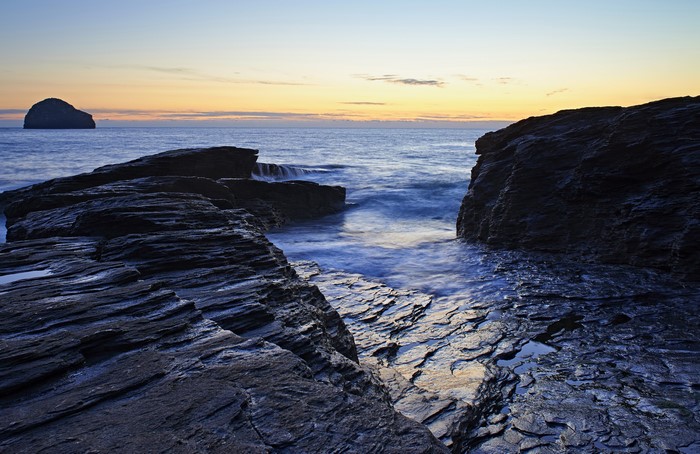 Rocky Coastline at Sunset with Distant Island