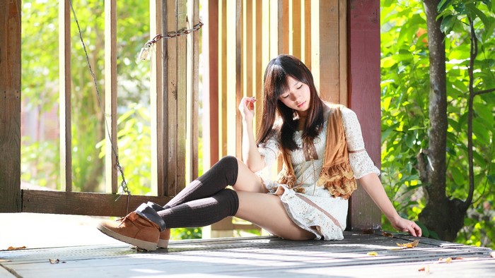 Young woman in knee-high socks sitting outdoors