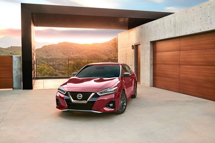 Red Nissan Maxima parked in modern driveway