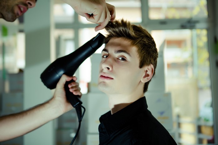 Man getting his hair styled with a hairdryer