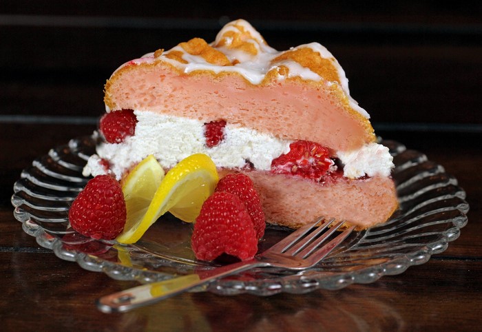 Slice of raspberry cake with lemon and raspberries on a plate