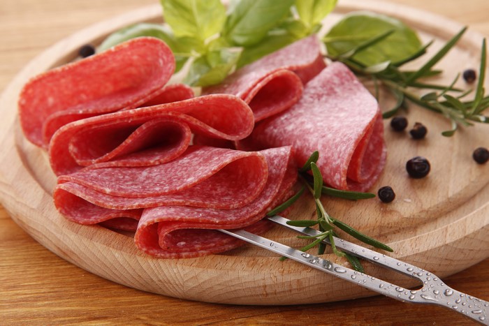 Sliced Salami with Basil and Rosemary on Cutting Board