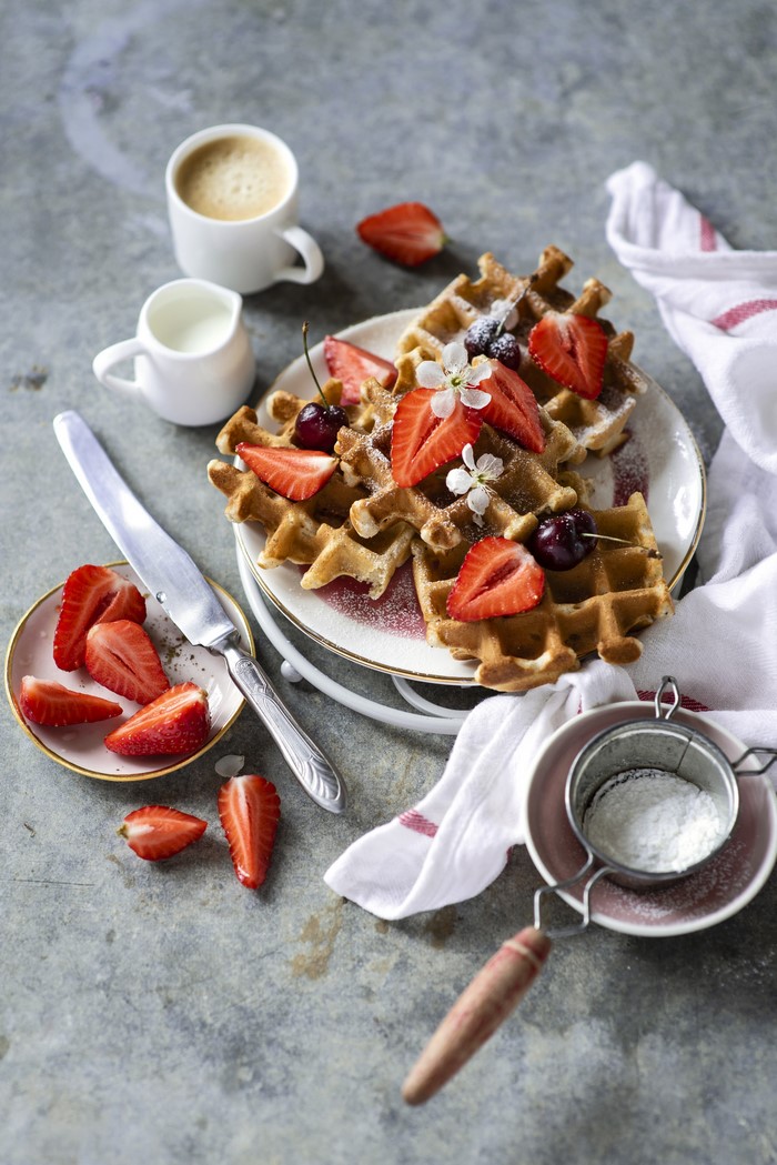 Waffles with strawberries and cherries, coffee, and cream
