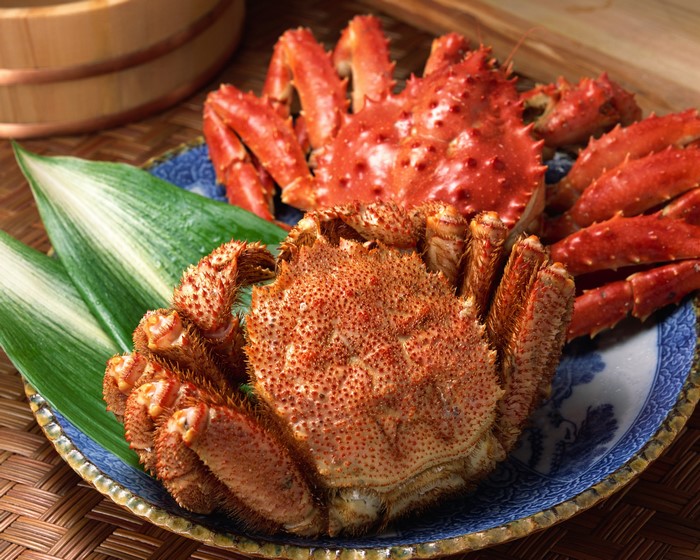 Two cooked crabs on a blue and white plate with green leaves